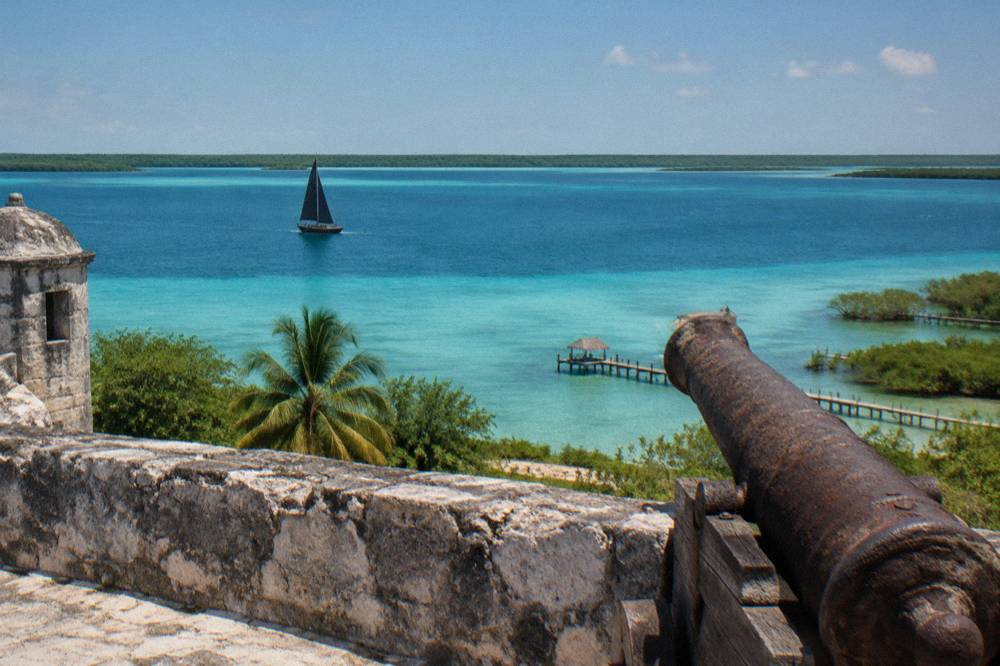 Sailboat with dark sails crossing wide open blue lagoon water