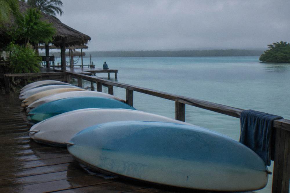 Row of paddleboards resting on a wooden dock beside still water at dawn