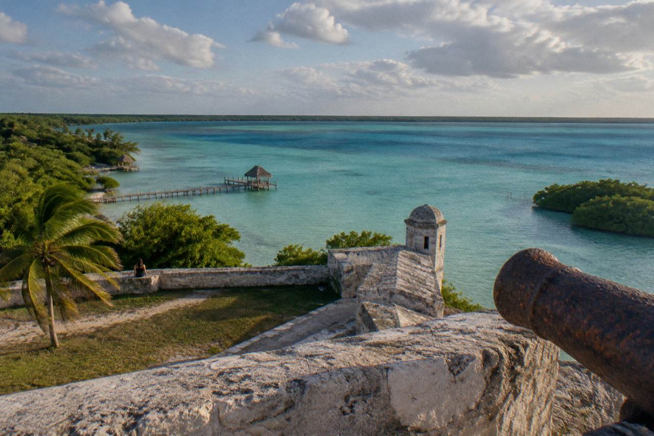 Calm turquoise freshwater lagoon stretching to a distant shoreline under a partly cloudy sky