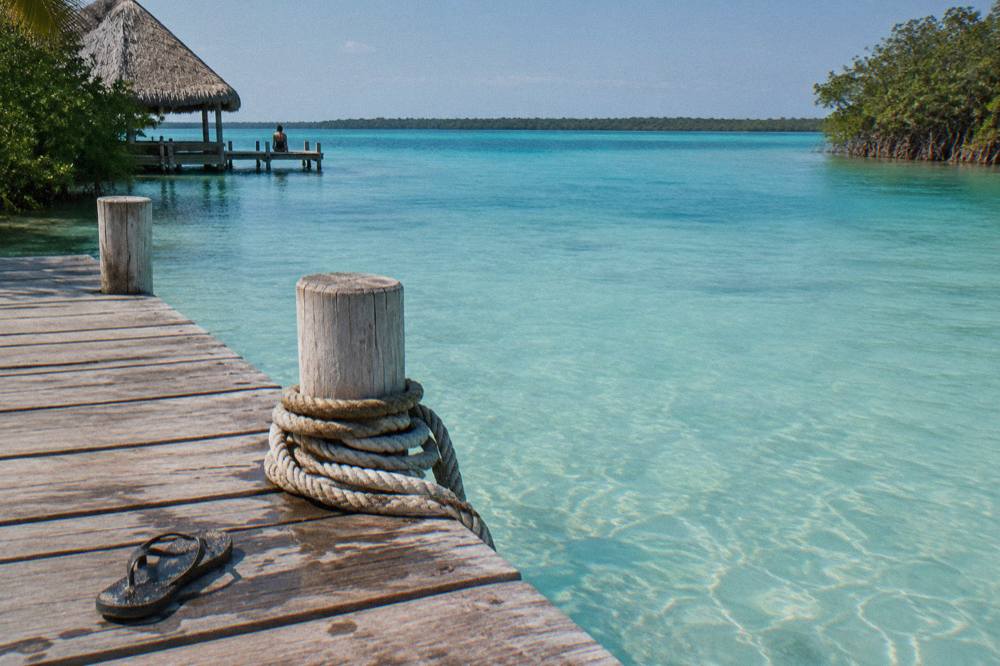 Calm turquoise shallows of Bacalar Lagoon along a wooden dock at morning