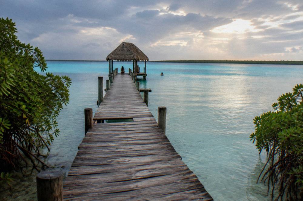 Wooden jetty extending over clear shallow turquoise water at Bacalar Lagoon