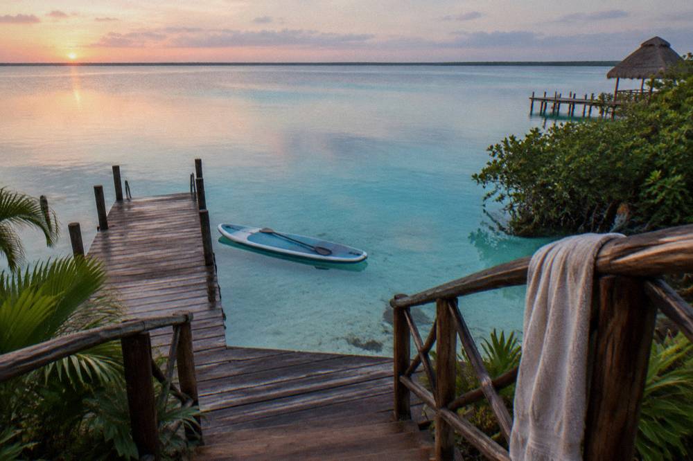A paddleboard floating on still turquoise water at first light on Bacalar Lagoon