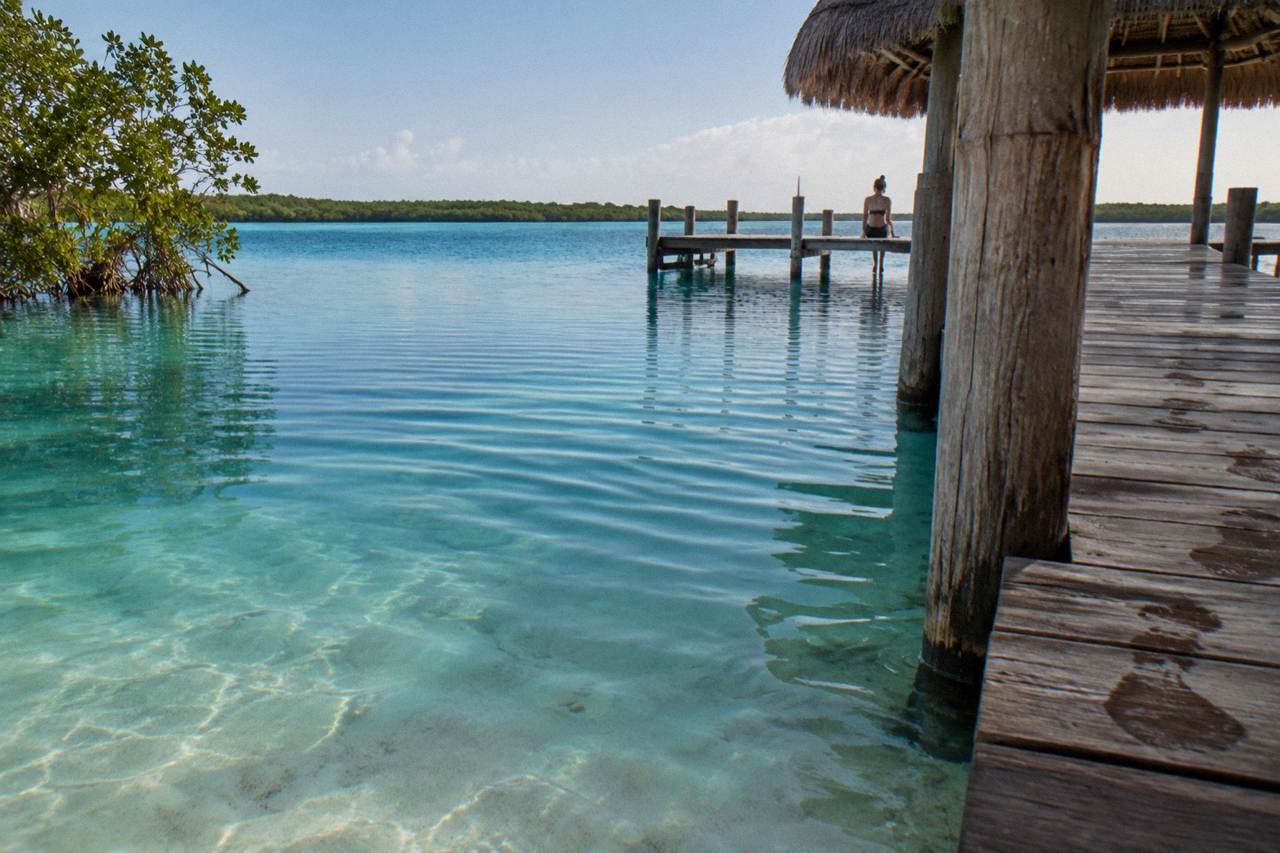 Calm turquoise water of Bacalar Lagoon under morning light, gentle ripples near a wooden dock