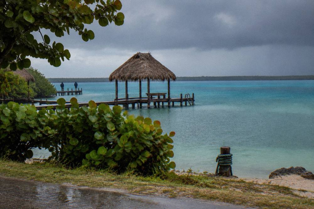 Grey rain clouds gathering above the turquoise water of Bacalar lagoon near a wooden dock