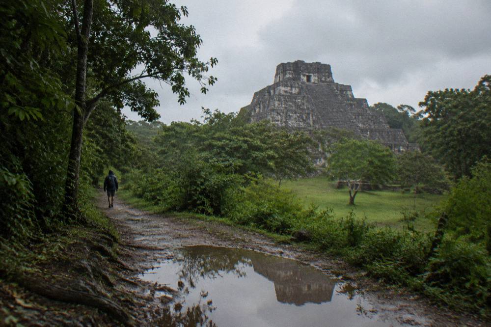 Ancient stone Mayan pyramid of Ichkabal rising above dense green forest under a cloudy sky