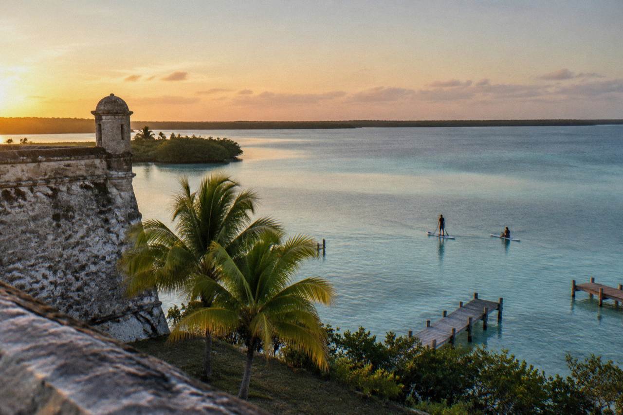 Two paddle boards gliding over calm turquoise water at first light on a freshwater lagoon