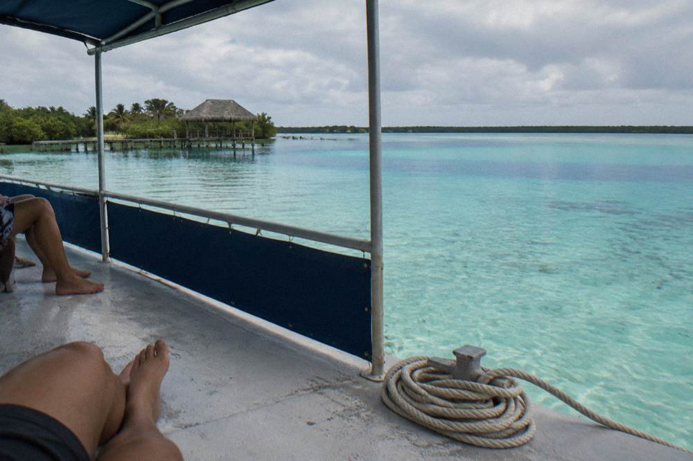 Guests on a pontoon boat passing over pale sand shallows in Bacalar Lagoon