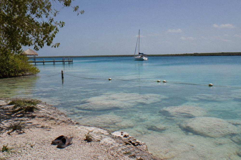 A sailing boat anchored near a rope buoy marking a protected zone on the lagoon