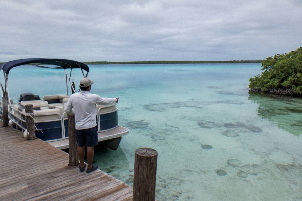 Guide pointing toward shallow water from the deck of a small boat on the lagoon