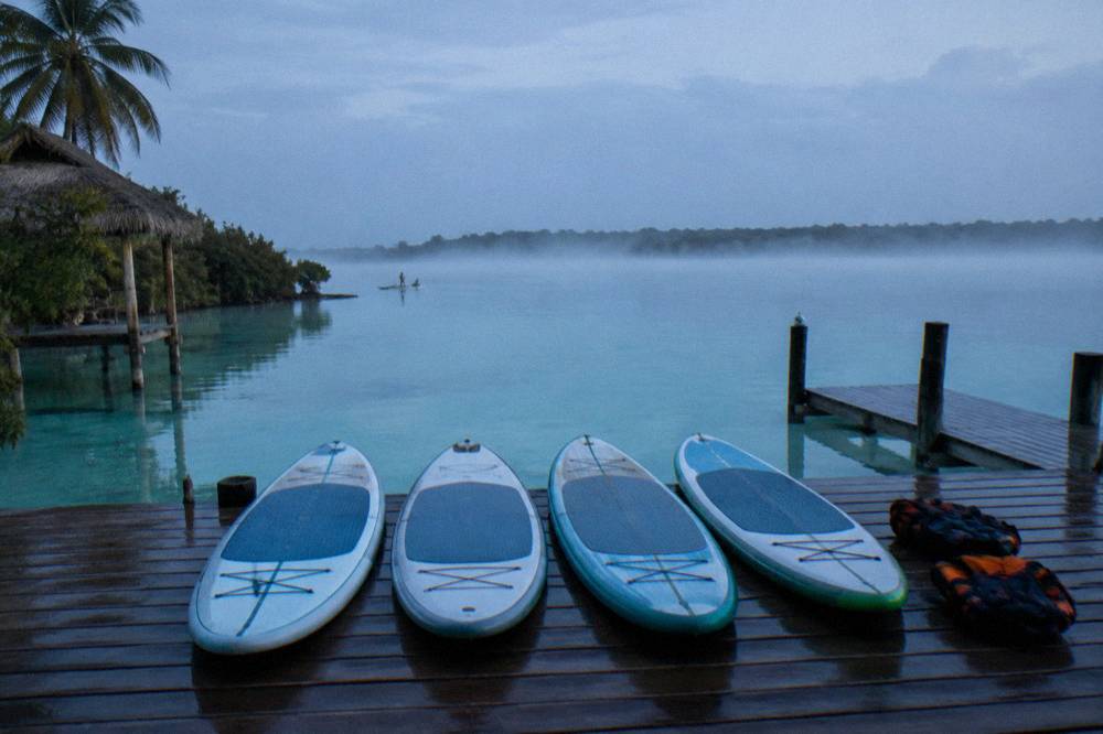 Paddleboards lined up on a dock at dawn before a sunrise tour on Bacalar Lagoon