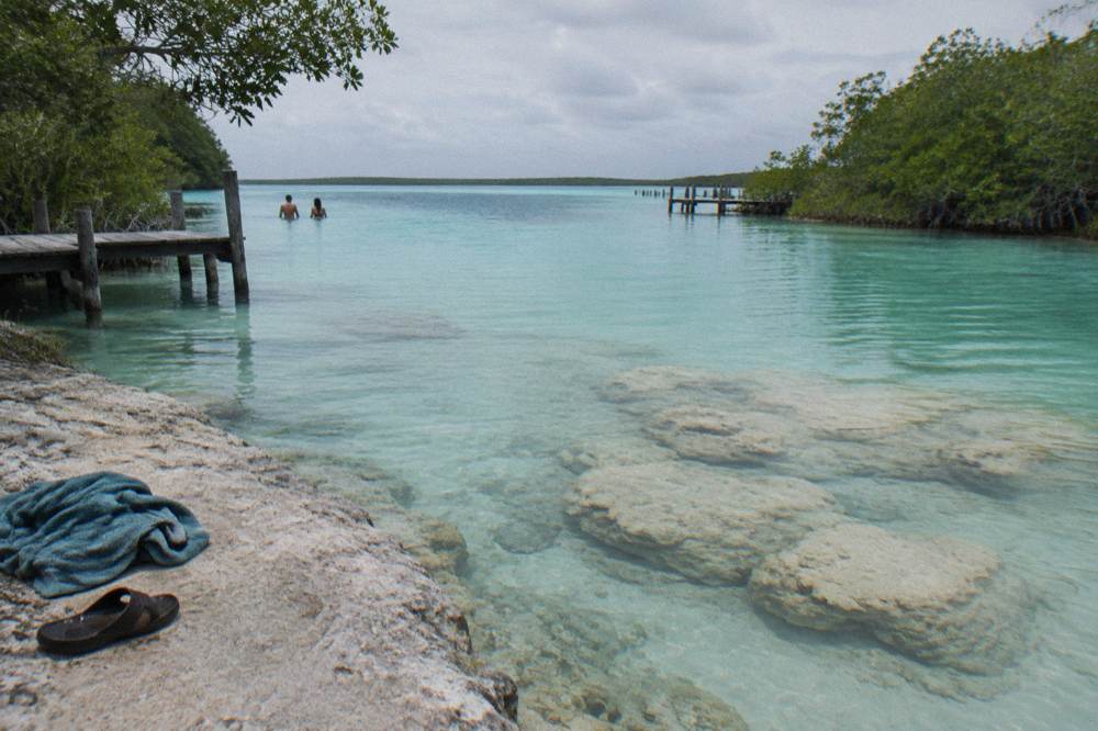Turquoise shallows of the lagoon narrowing into a tree-lined channel