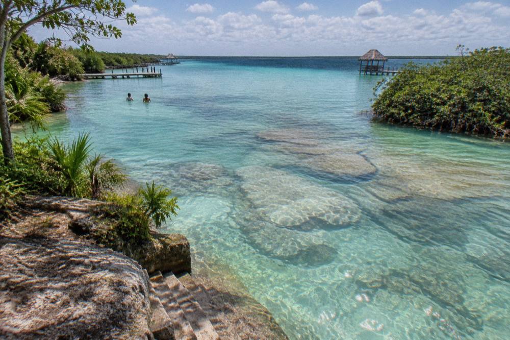 Clear shallow water of Los Rapidos channel flowing over pale rock in bright daylight