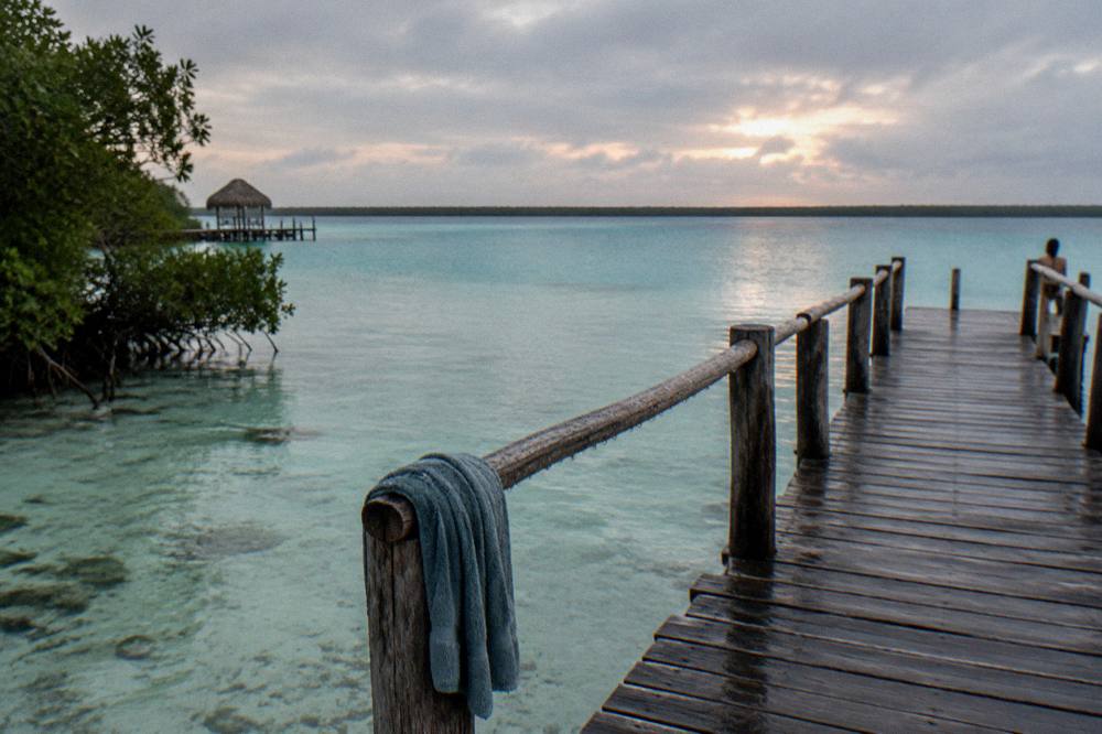 Sunrise light over calm lagoon water with a wooden pier in the foreground
