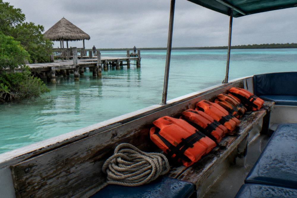 Orange life vests stowed on the bench of a small tour boat on the lagoon