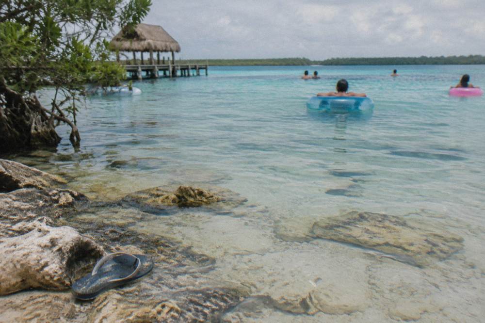 Shallow turquoise channel of Los Rapidos with white limestone bed and rings floating on gentle current