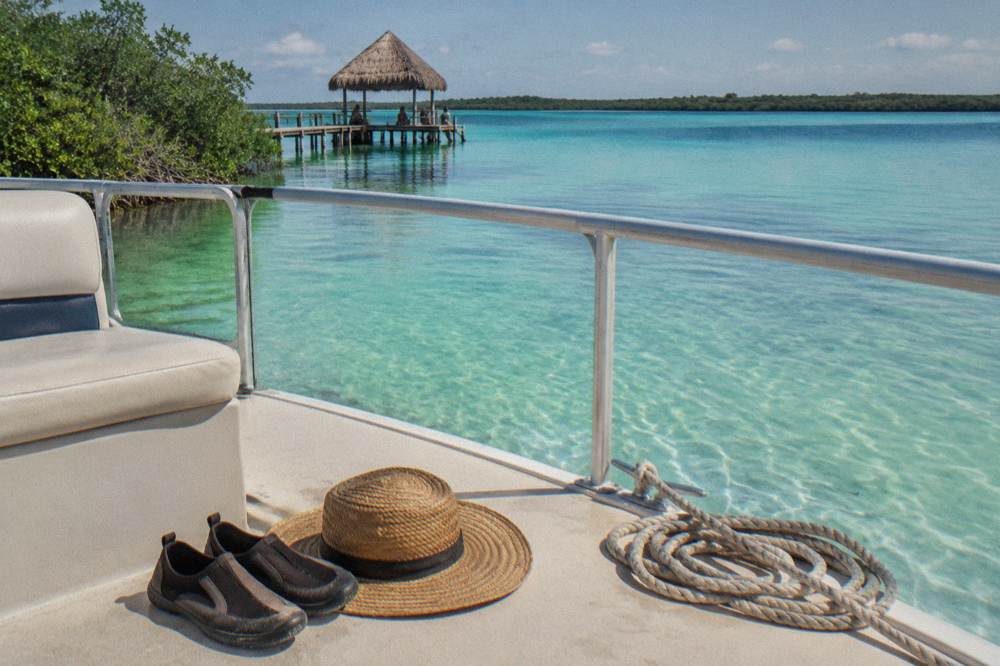Water shoes and a sun hat set on the deck of a pontoon boat on calm turquoise water