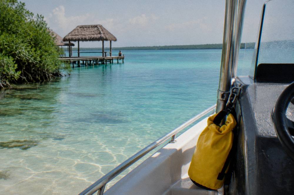 A small dry bag clipped to the console of an open boat carrying fruit and drinks on the lagoon
