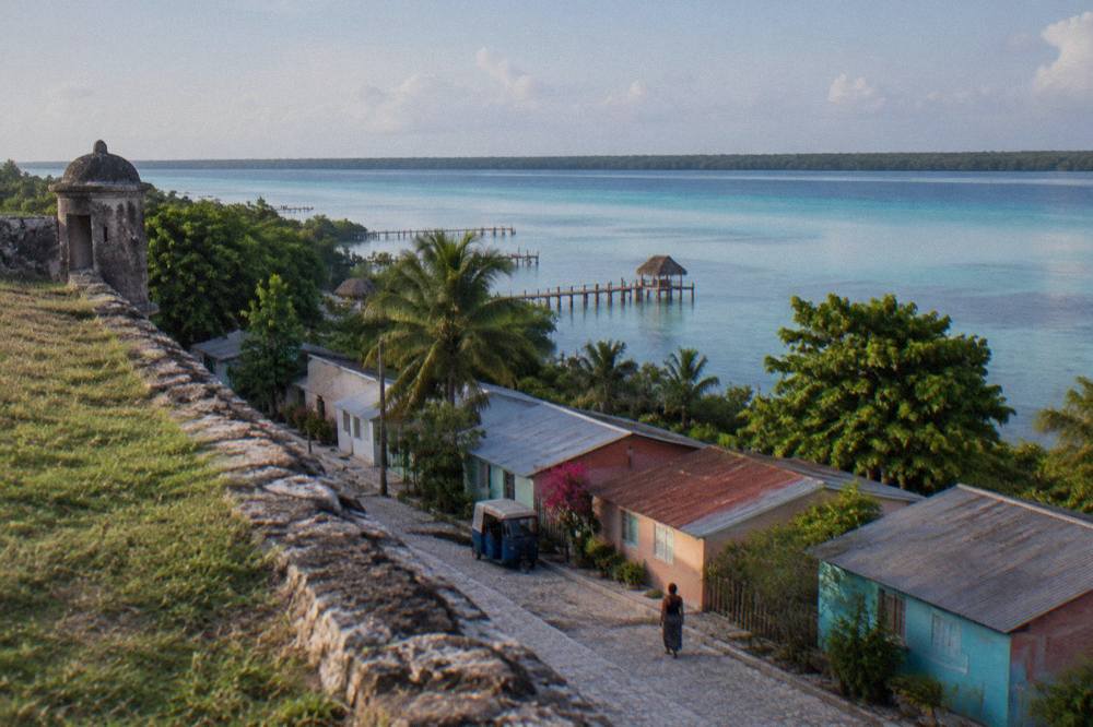 Quiet street of low colorful buildings in Bacalar town in early morning light