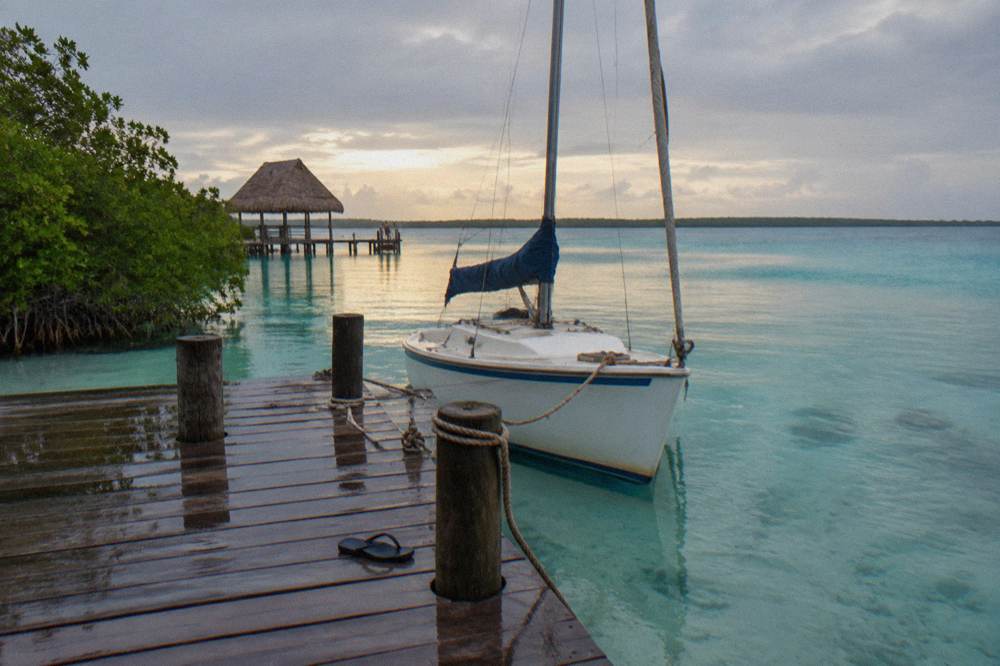 Small sailing boat moored at a wooden pier on the lagoon boulevard