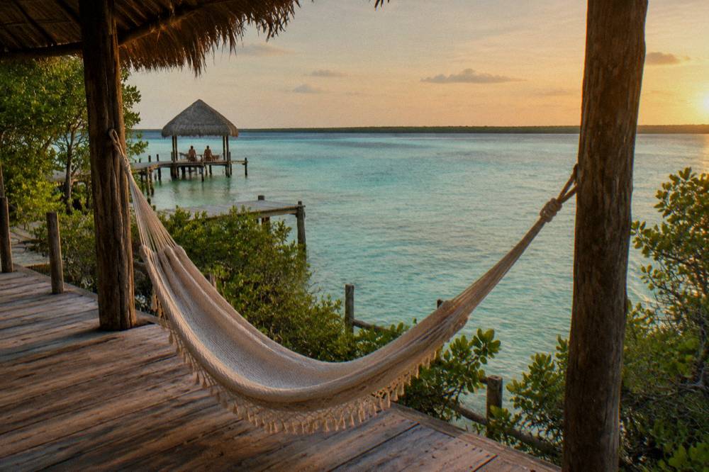 Hammock on a lagoon-facing deck with turquoise water beyond