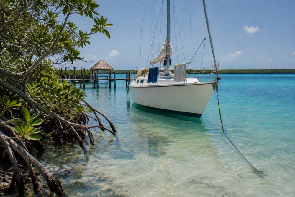 Private sailboat moored beside mangroves in clear shallow lagoon water